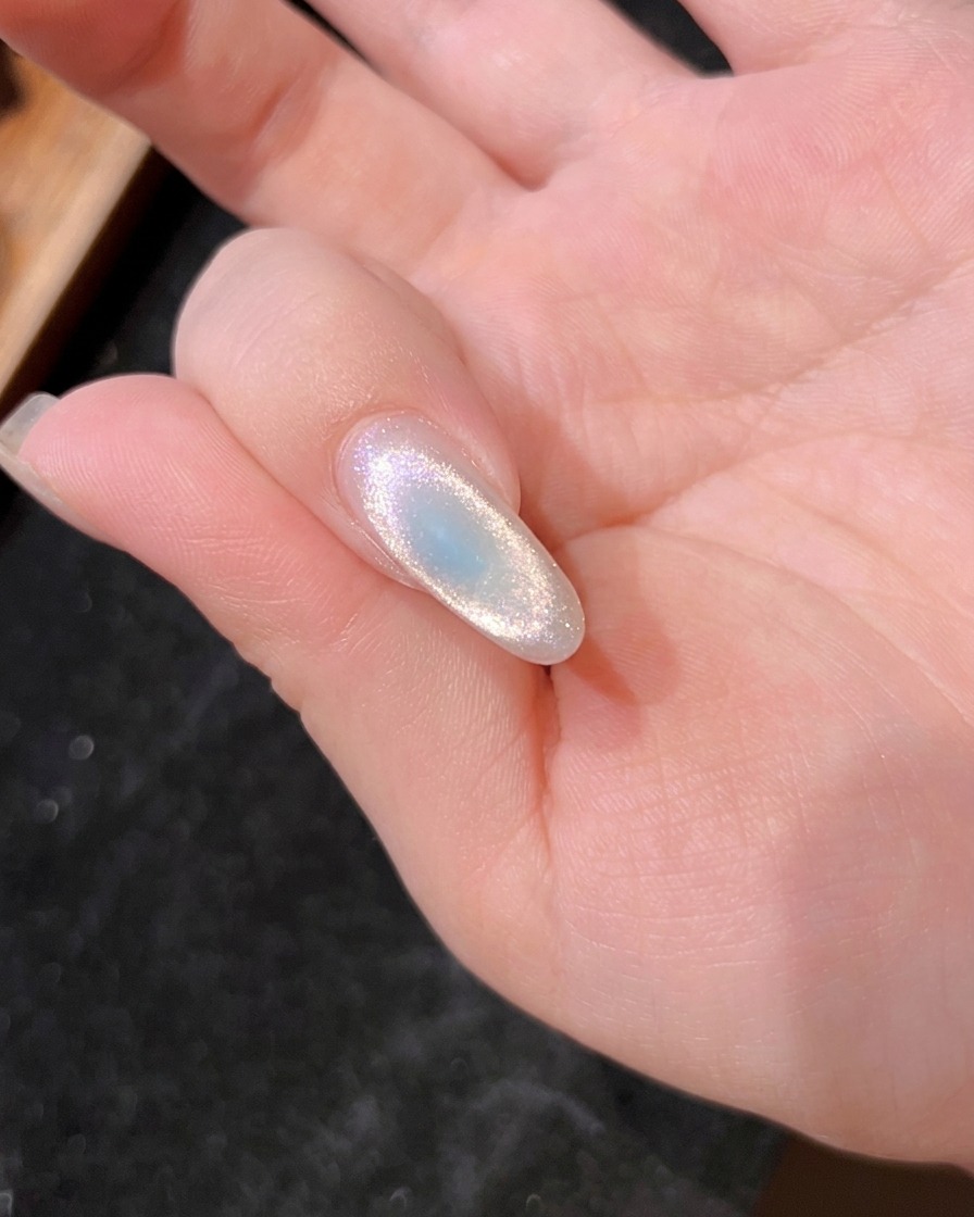 Vista ravvicinata di ununghia sotto la lampada UV, che mostra il gel blu in fase di polimerizzazione.