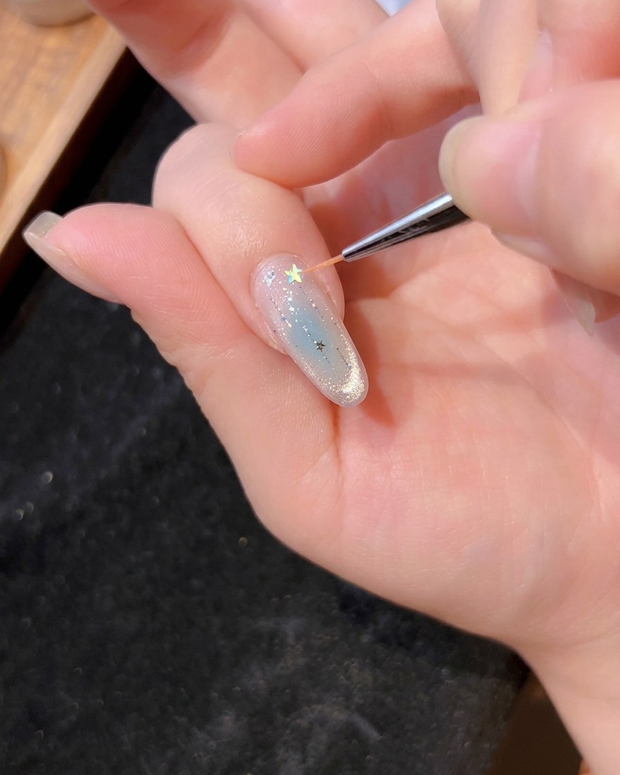 Un pennello sottile che posiziona un glitter a stella olografico sul gel bagnato di ununghia manicure.