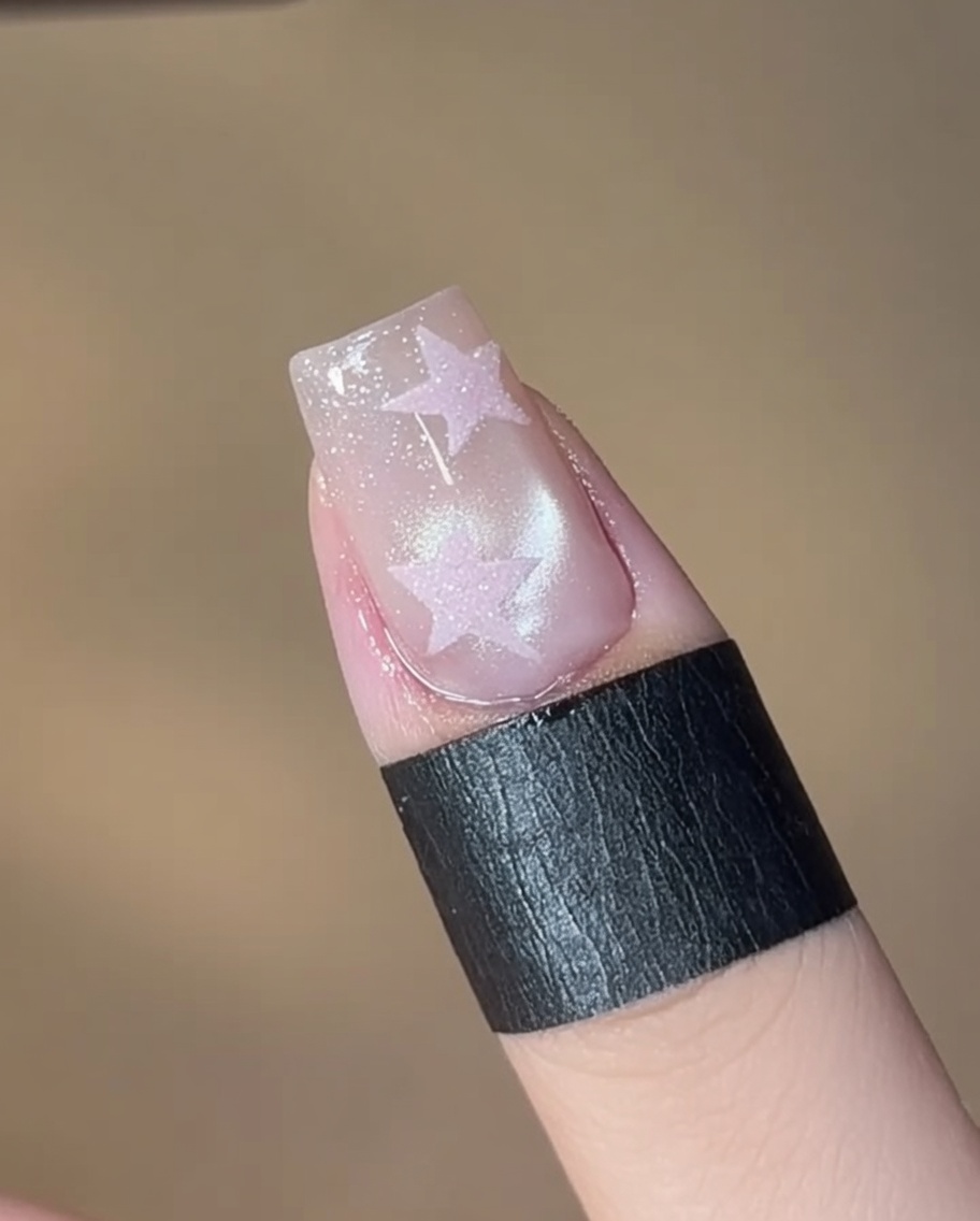 Un pennello che applica uno smalto gel cat-eye shimmer 05 su una lamina ungueale pulita.
