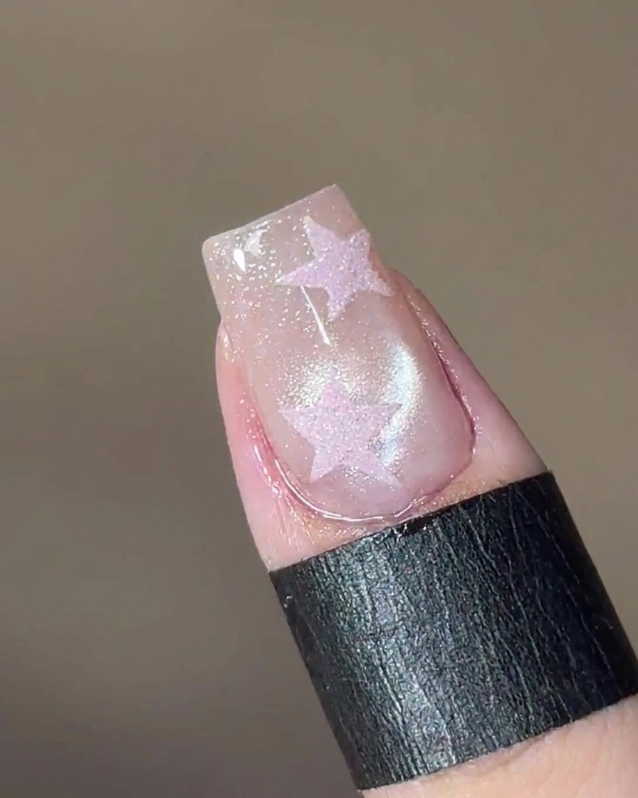 Un magnete tenuto sopra lunghia, facendo sì che le particelle brillanti nel gel formino un effetto a perla di vetro.