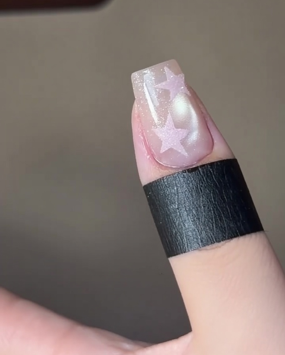 Dita che polimerizzano un design di unghie a stella sotto una lampada UV professionale.