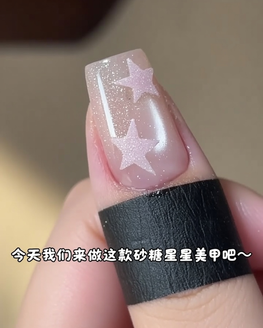 Un piccolo pennello che applica gel rosa allinterno di uno sticker a stella su ununghia.