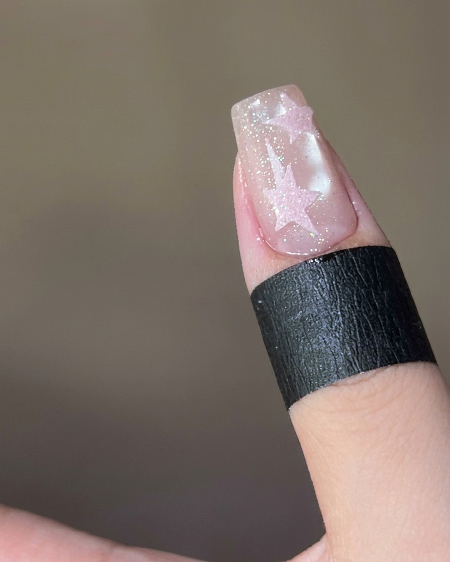 Polvere di zucchero rosa cosparsa su una stella ricoperta di top coat bagnato su ununghia.