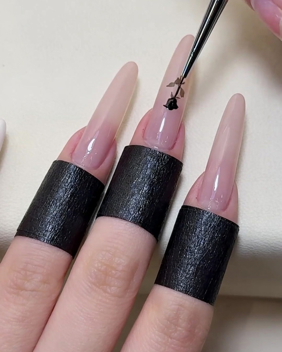 Un pennello di precisione a punta fine traccia e riempie i dettagli della rosa bianca usando uno smalto gel nero.
