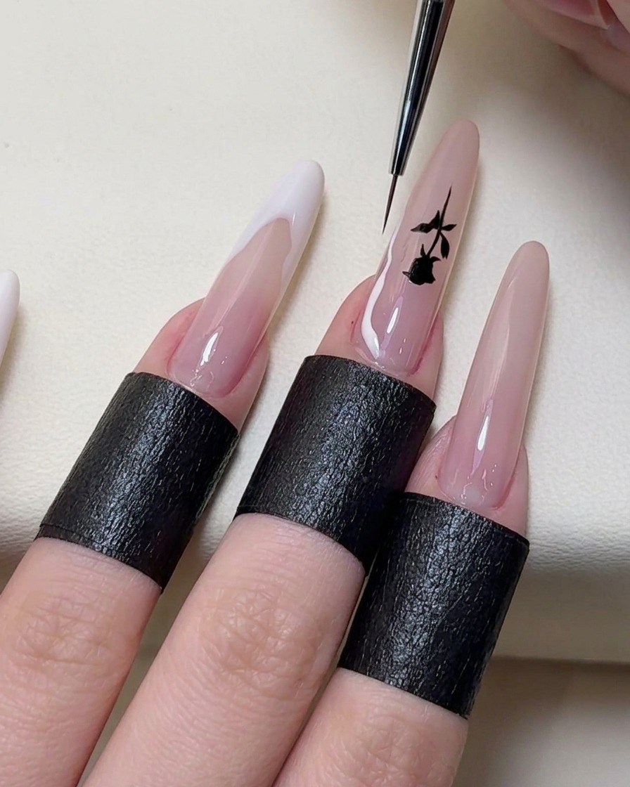 Un pennello sottile per nail art dipinge linee French irregolari bianche sulle estremità delle unghie.