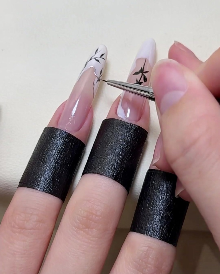 Un pennello per nail art applica un tocco di argento metallizzato lungo il bordo dei rami dipinti.