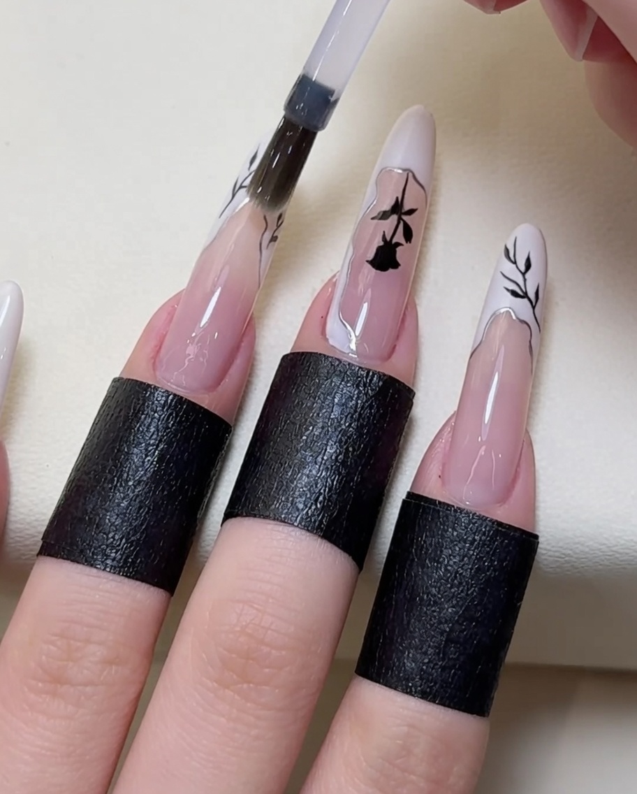 Un pennello applica un ultimo strato di top coat trasparente sopra la nail art finita.