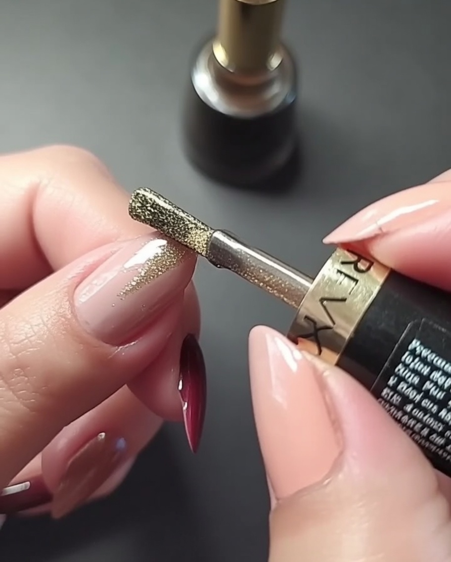 Primo piano di una mano che dipinge una precisa linea oro verticale al centro dellunghia rosa antico.