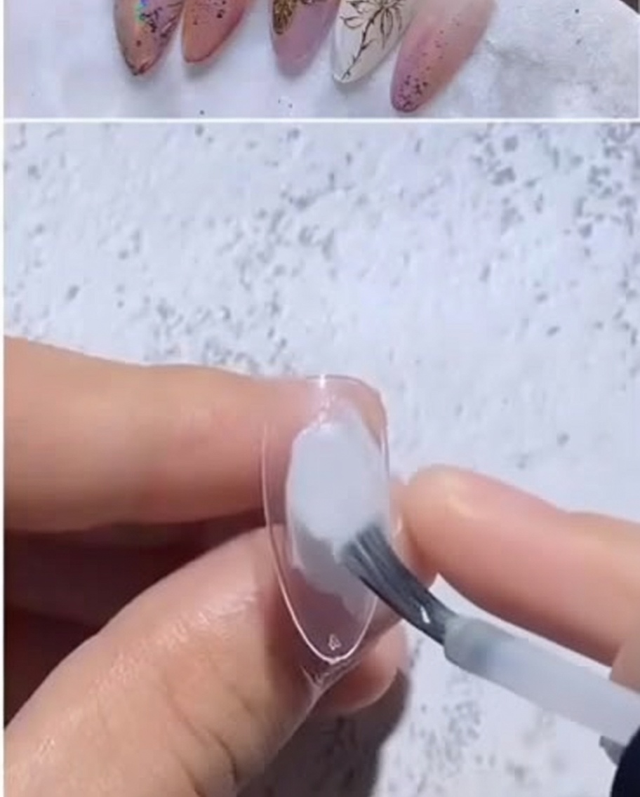 Primo piano di una tip a mandorla trasparente su cui viene applicata una goccia di gel bianco latte.