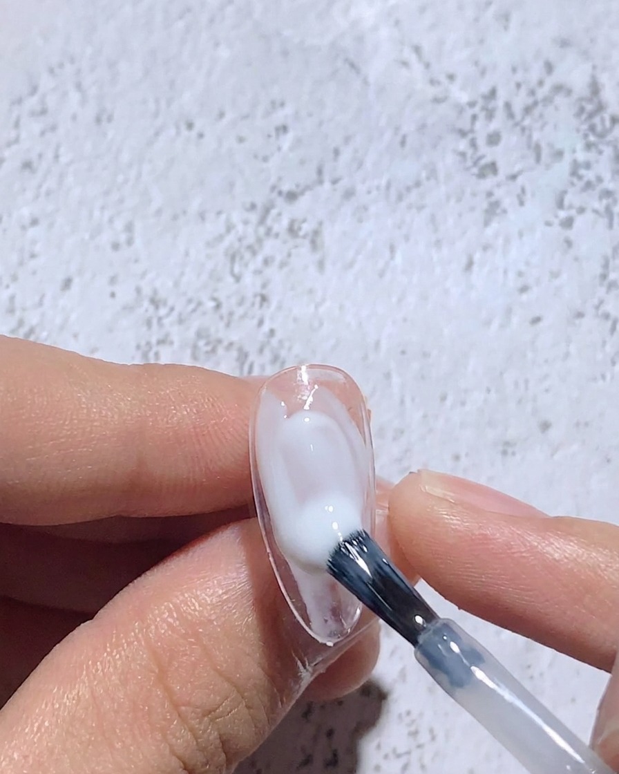Un pennello fine sfuma il gel bianco umido per creare un effetto soffuso al centro dellunghia.