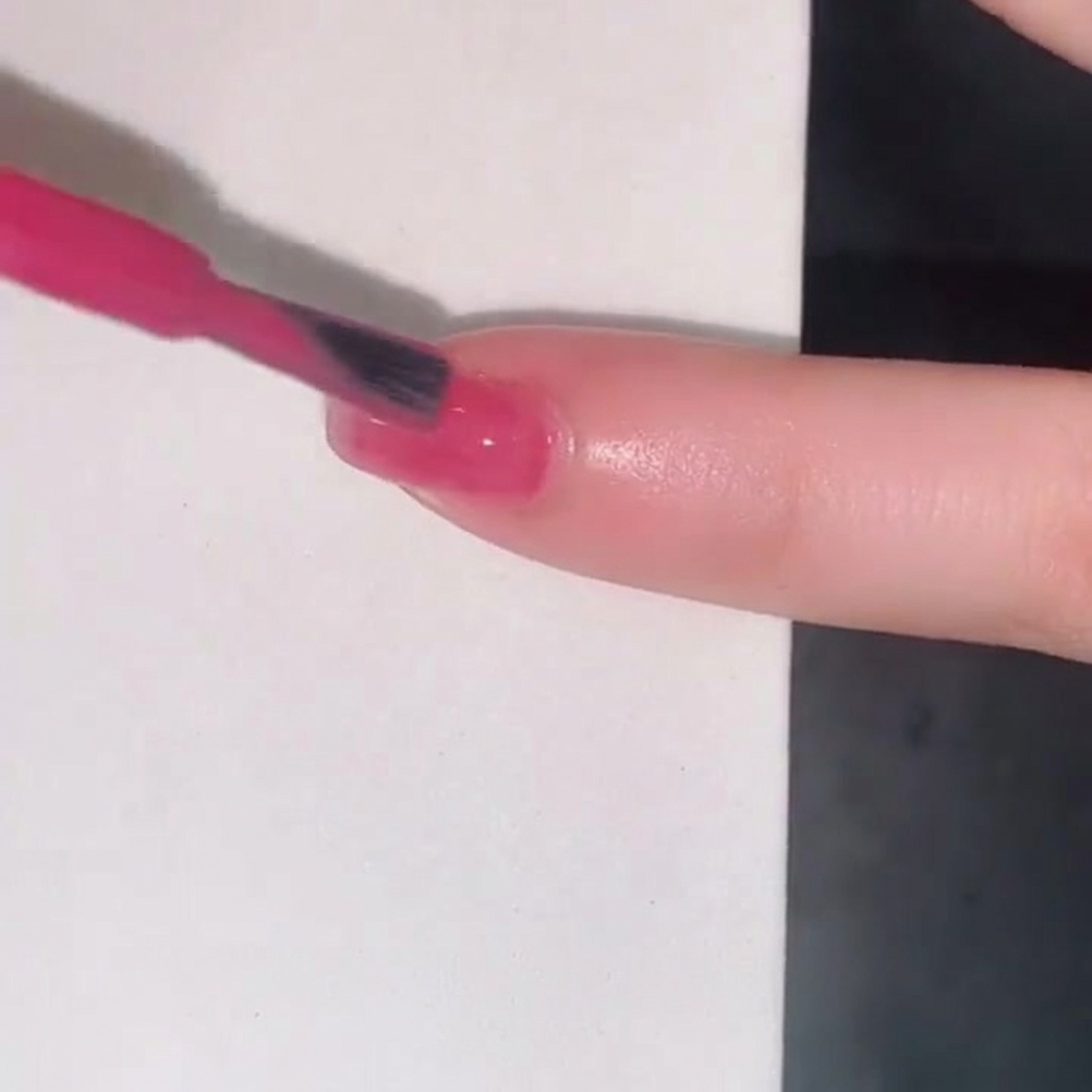Un pennello da smalto che aggiunge un terzo strato di gel jelly rosa per aumentare lintensità del colore sullunghia.