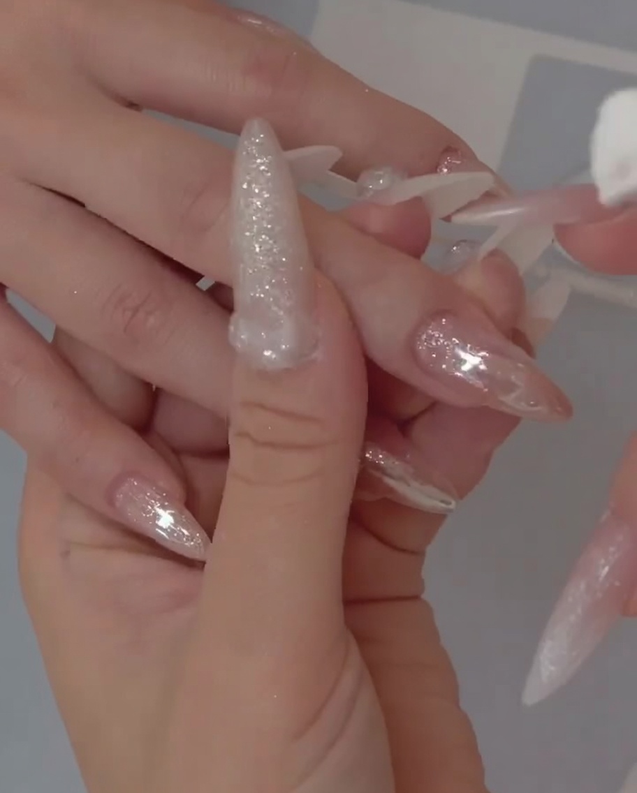 Primo piano di un pennello che applica una base gel jelly semitrasparente su ununghia naturale.