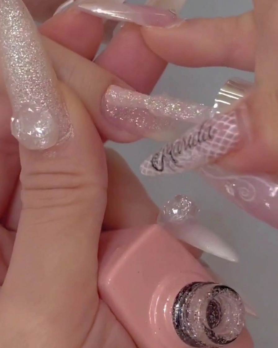 Pennello che applica uno strato di top coat trasparente sopra ununghia con glitter.