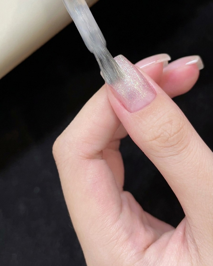 Applicazione dello smalto gel cat-eye bianco velato sulla superficie dellunghia.