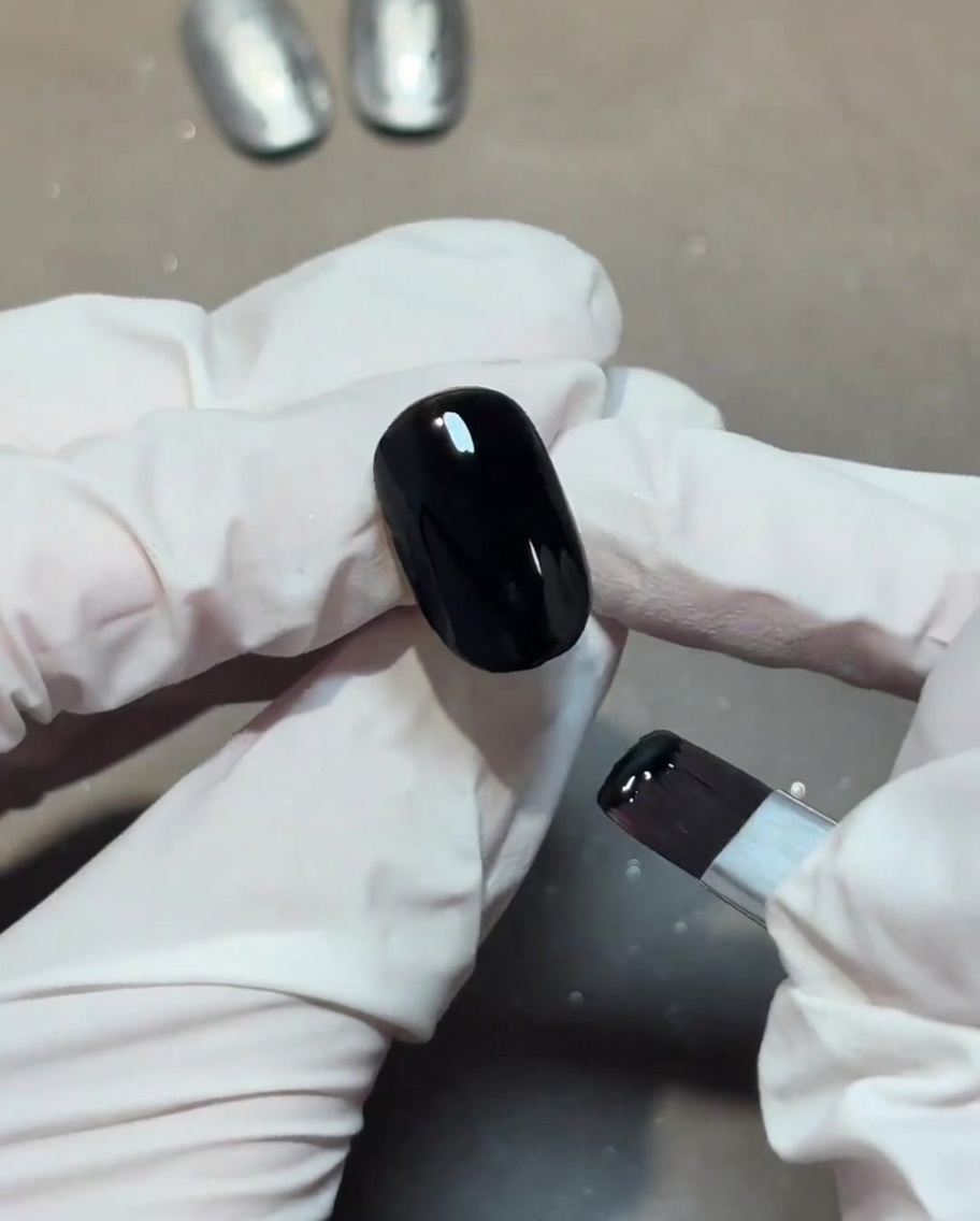Applicazione di un top coat trasparente e lucido sopra una base nera.