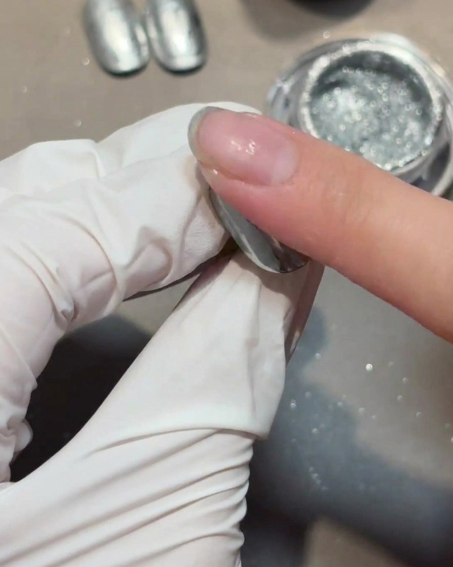 Applicazione di uno strato di gel di rinforzo trasparente sopra ununghia con effetto chrome.