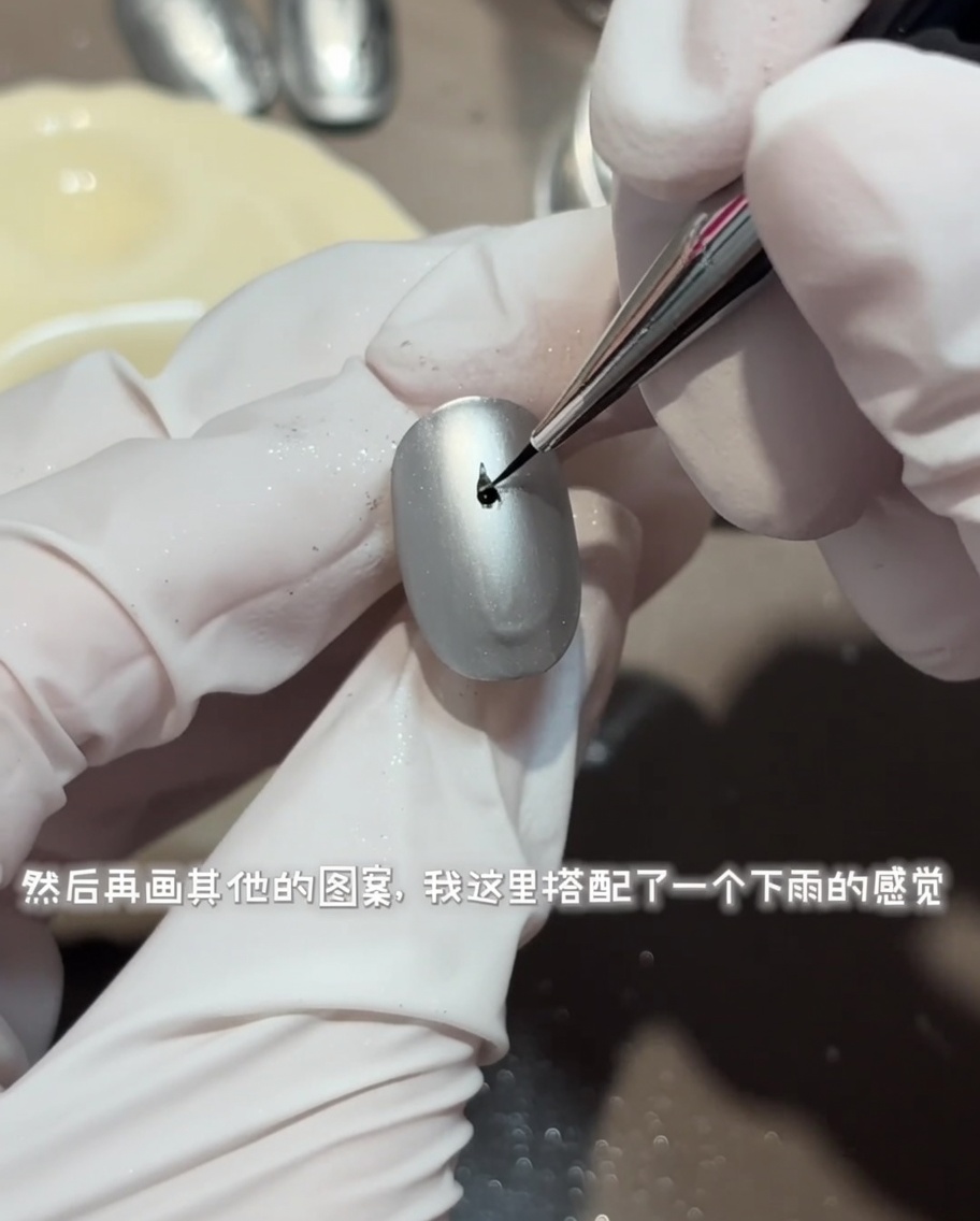 Un pennello liner che disegna un dettaglio circolare di increspature dacqua con top coat lucido su ununghia grigio opaco.
