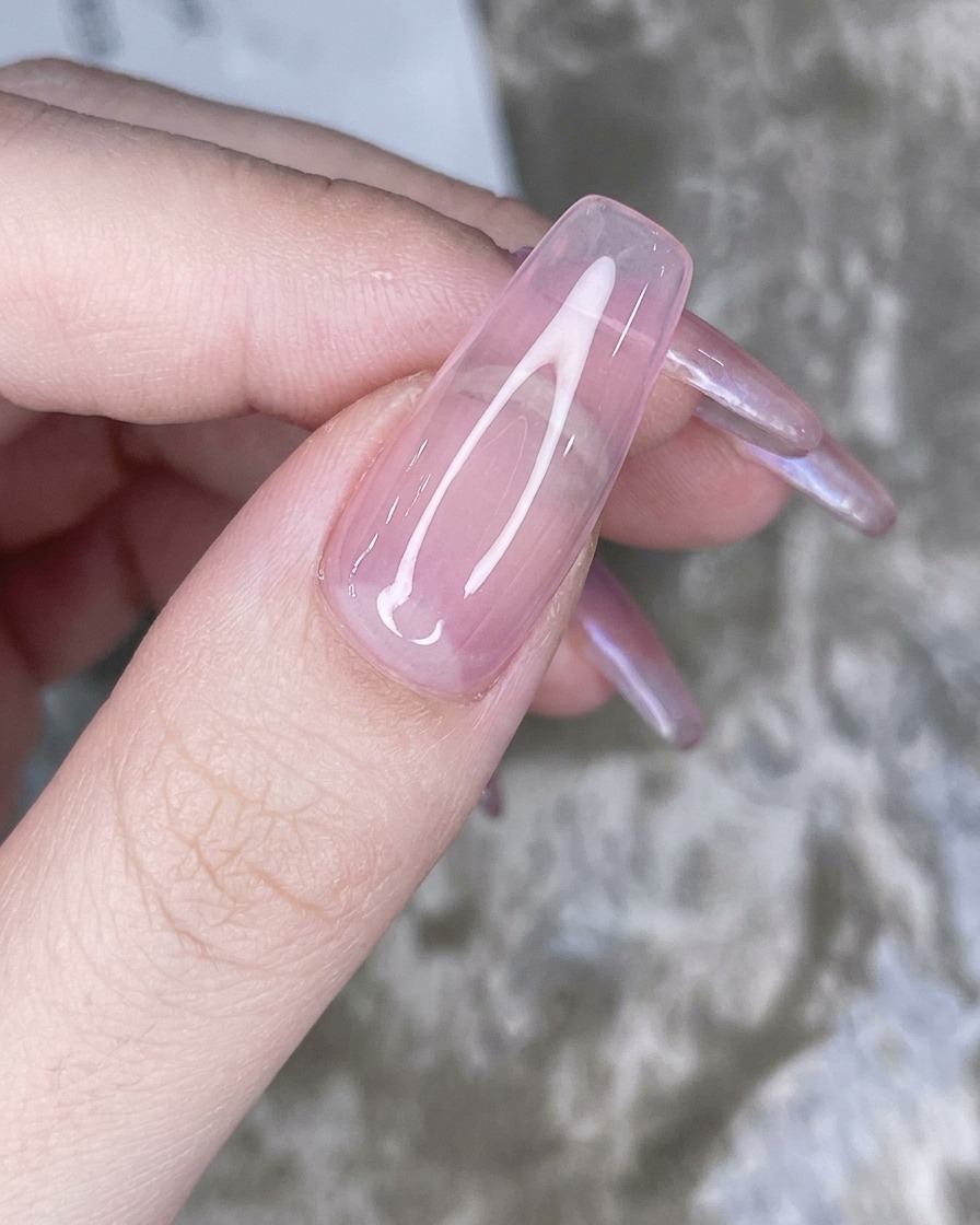 Un applicatore a spugnetta che tampona la polvere cromo iridescente sulla punta dellunghia rosa.
