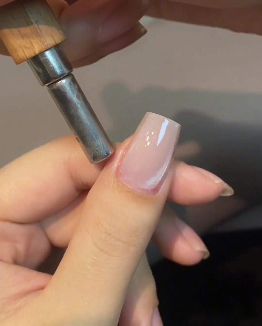 Un magnete cilindrico tenuto vicino al lato dellunghia per muovere i riflessi del cat eye.