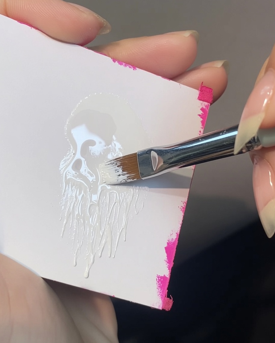 Un pennello angolato che preleva del gel painting bianco dalla tavolozza.