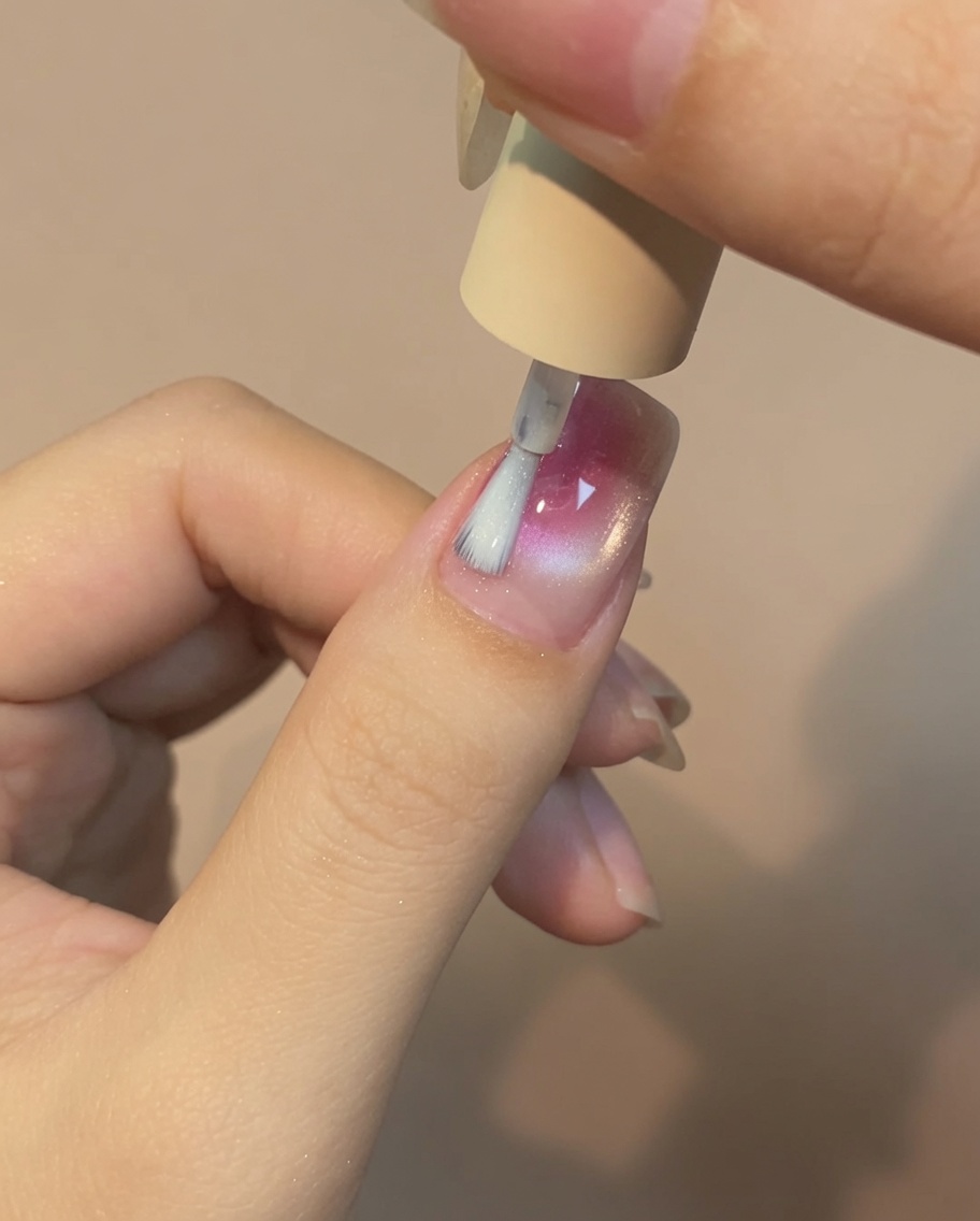 Un pennello che applica uno strato sottile di top coat no-wipe sullunghia.
