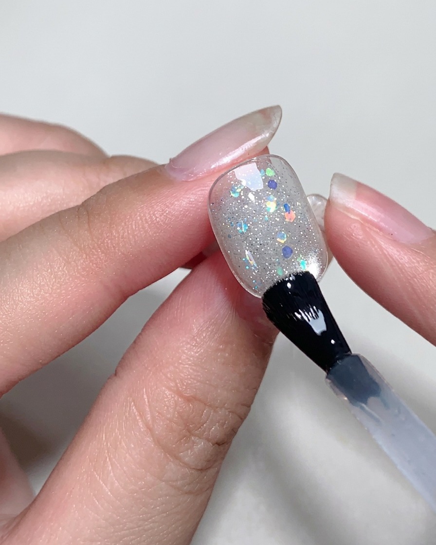 Applicazione di uno strato sottile di blooming gel trasparente sulla superficie dellunghia.