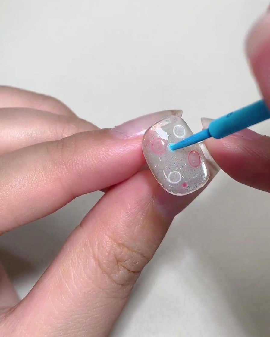 Uno strumento dotting posiziona piccole bolle colorate sulla superficie dellunghia.