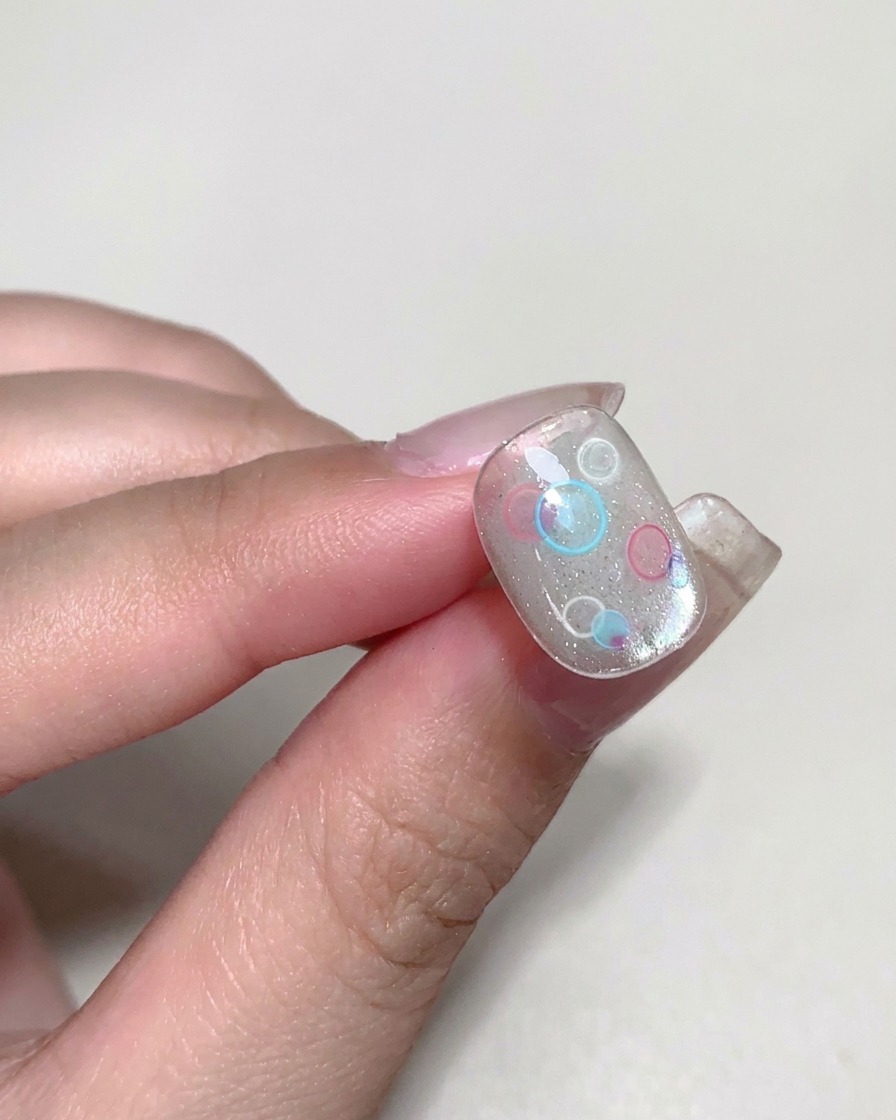 Un pennello applica un builder gel trasparente e viscoso sopra il design decorato.