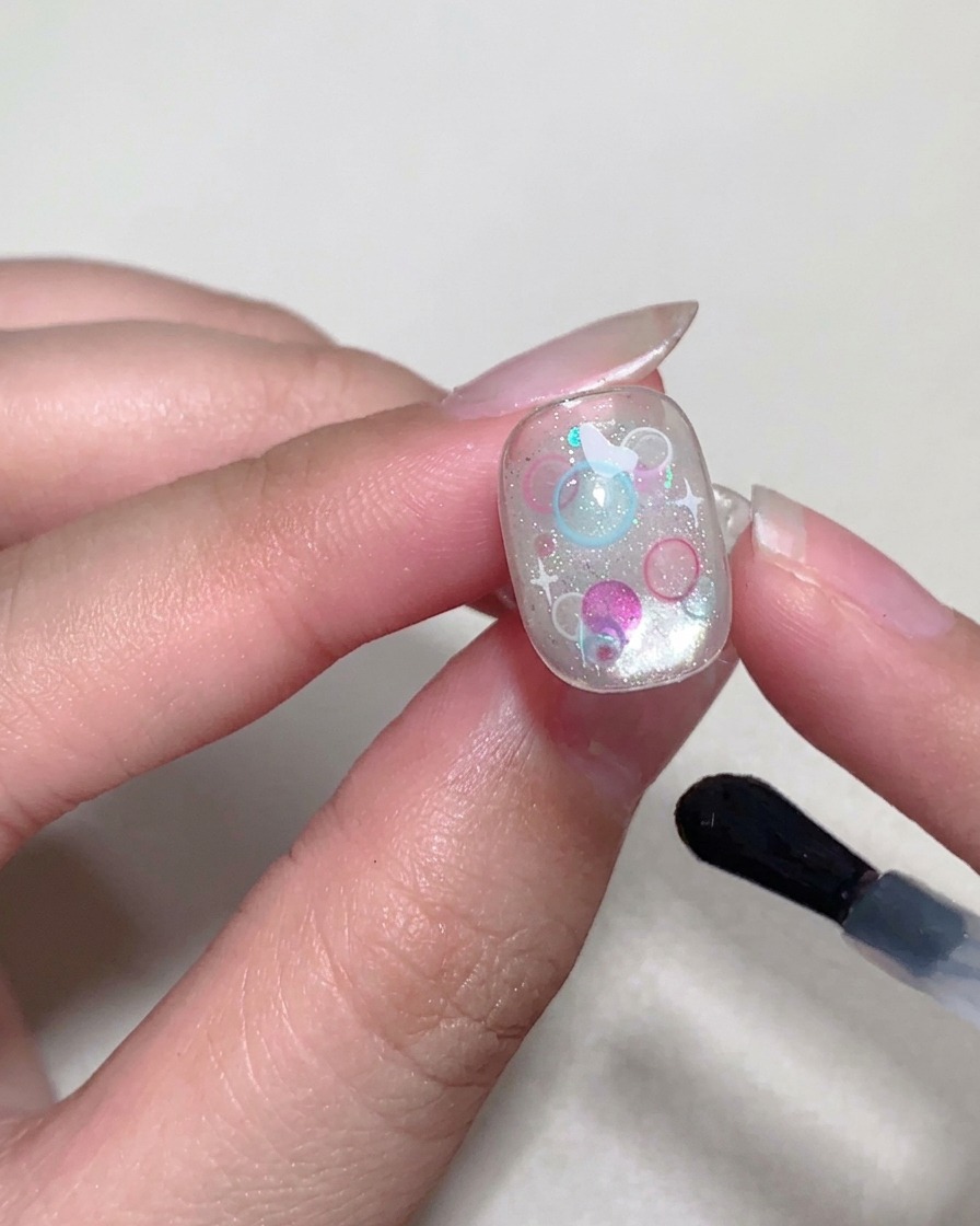 Un pennello applica un top coat finale lucido sulla superficie dellunghia.