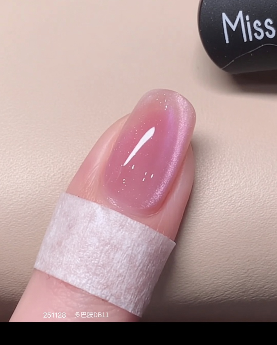 Un pennello applica una seconda passata abbondante di smalto cat eye rosa sopra lo strato precedentemente polimerizzato.