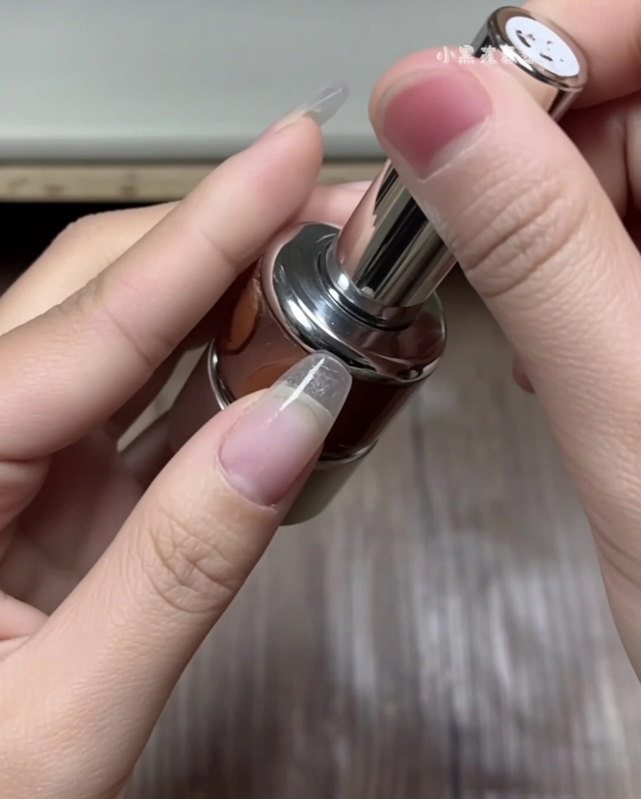 Una mano che usa le pinzette per selezionare un adesivo curvo per french tip da un foglio di linee guida bianco.
