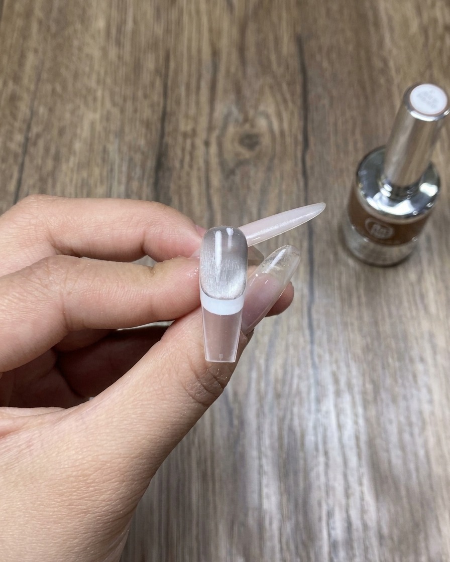 Una mano appoggiata allinterno di una lampada UV/LED professionale, che polimerizza la nail art cat eye appena applicata.