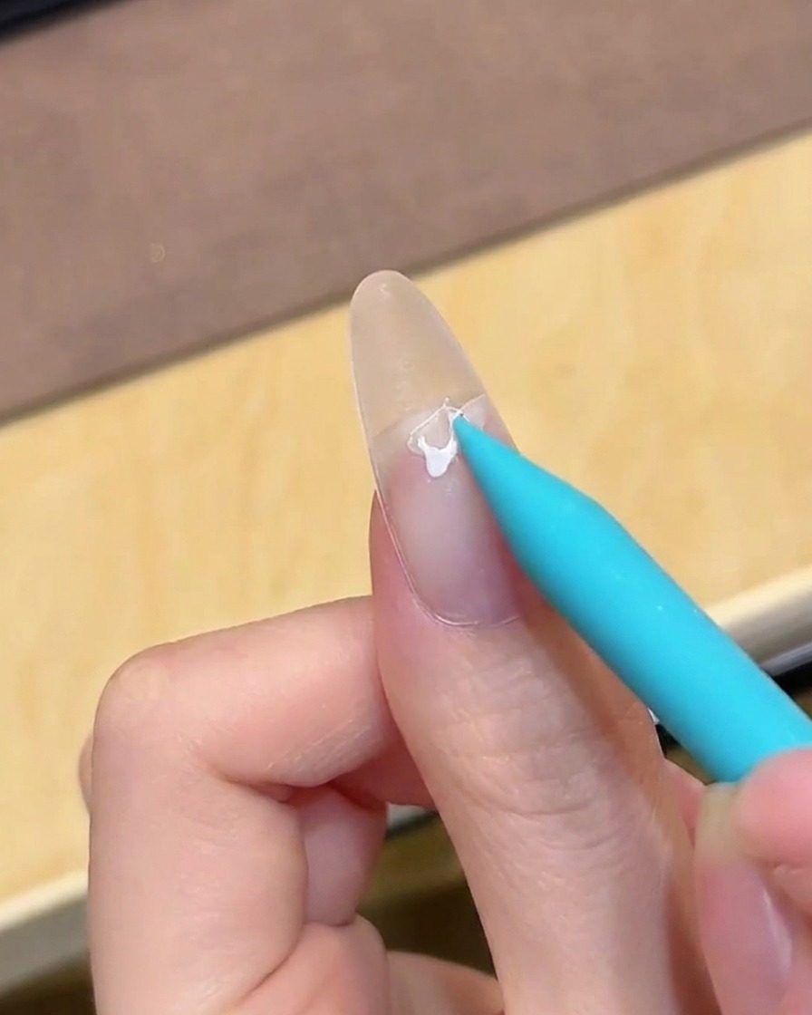 Un pennello che applica un gel di base trasparente su ununghia pulita e naturale.