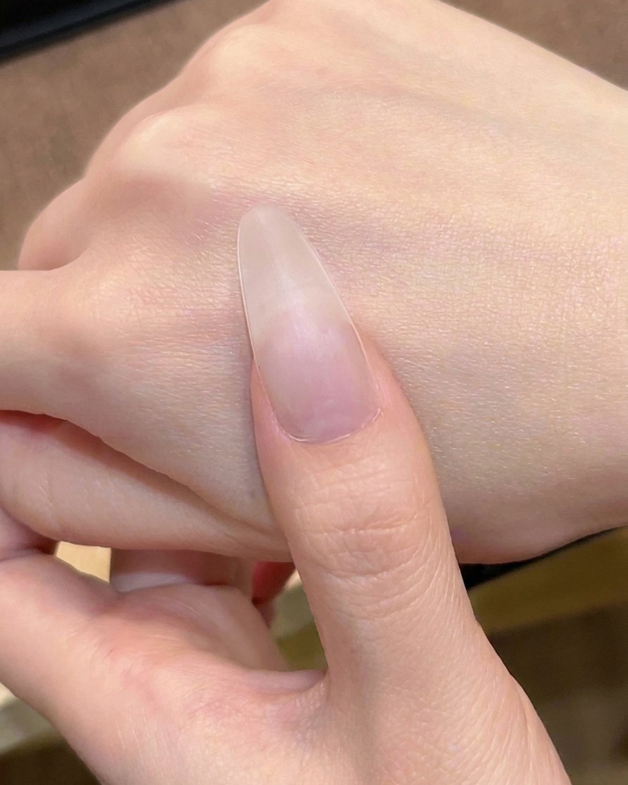 Il primo strato di gel rosa carne traslucido viene applicato sullunghia con un pennellino.