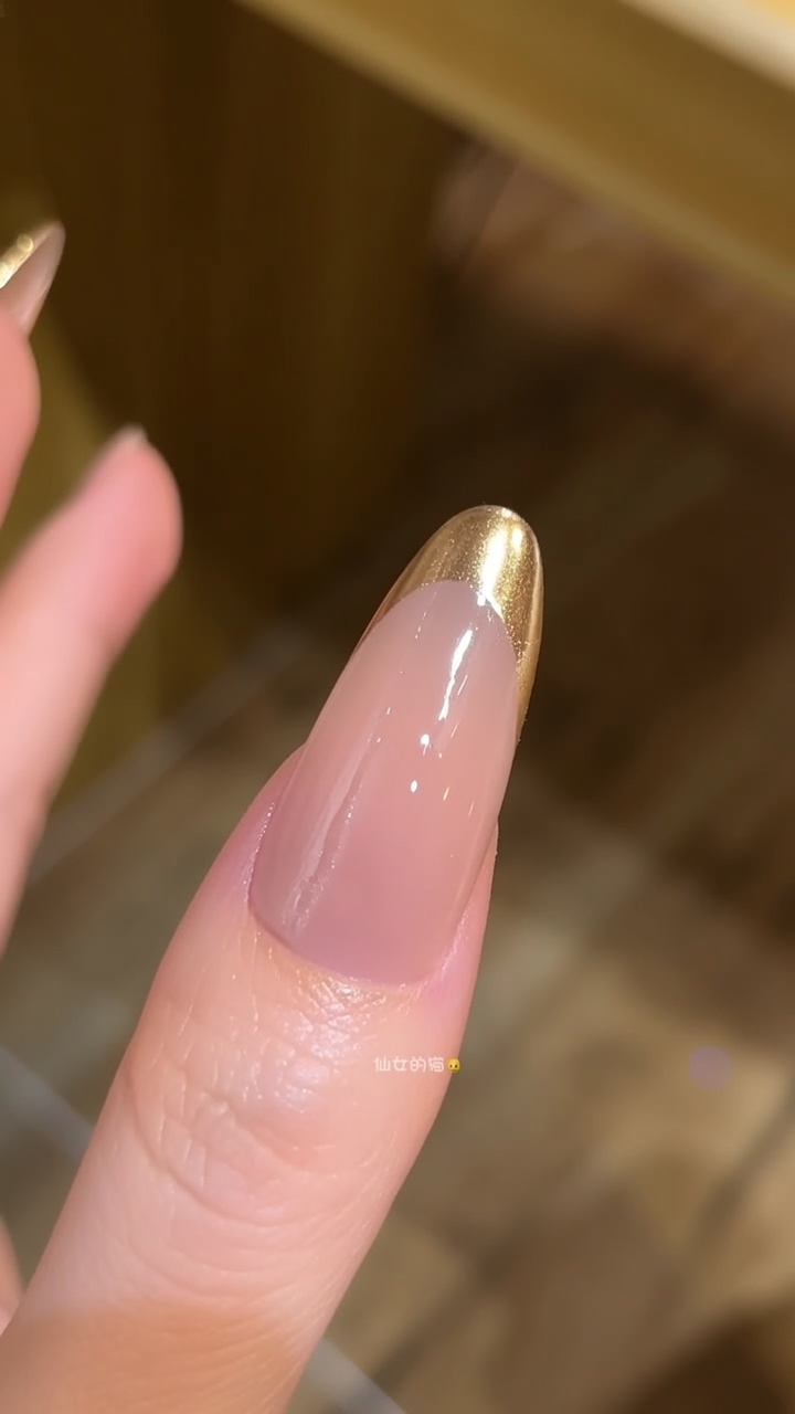 Splendide unghie lunghe a mandorla caratterizzate da una base nude lucida e una punta French cromata oro ad effetto specchio.