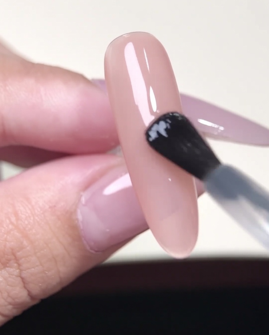 Pinzette che posizionano uno sticker per French manicure su ununghia gel color nude.