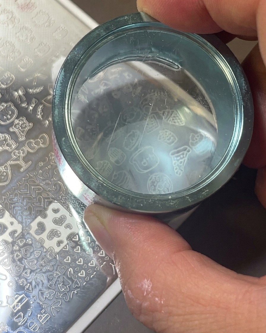 Un timbro trasparente in silicone che preme sulla piastra metallica per trasferire licona bianca.