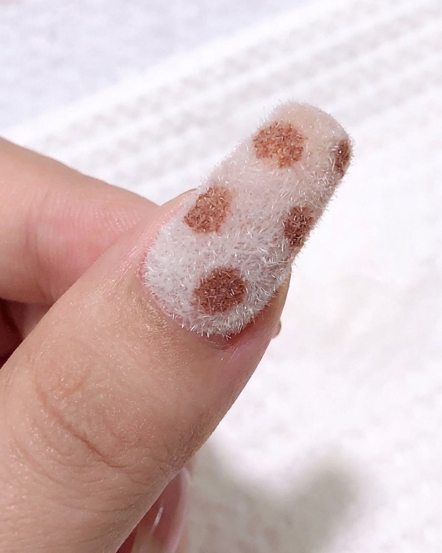 Primo piano con un pennello a punta fine che applica gel nero per creare il motivo delle macchie leopardate sulla superficie vellutata.