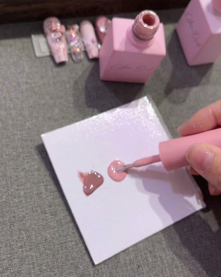 Carta da palette con tre gocce distinte di gel nei colori marrone, rosa medio e rosa chiaro.