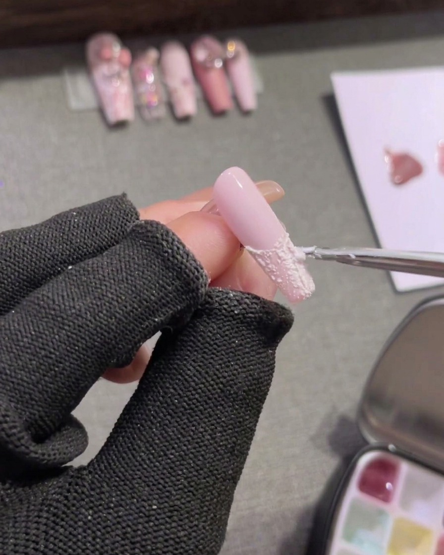 Un pennello riempie la punta di ununghia rosa con gel plastilina bianco opaco.