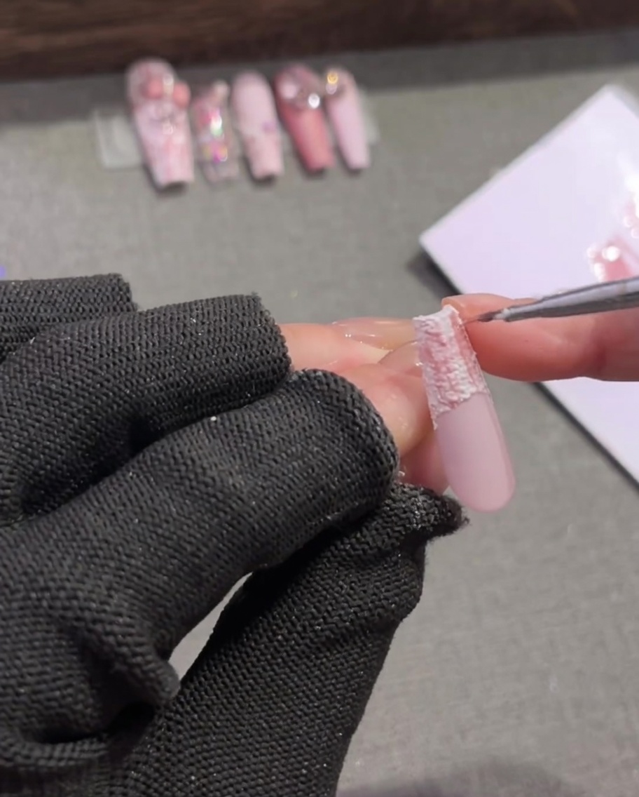 Un pennello aggiunge sottili linee marroni incrociate su un motivo tartan rosa e bianco.