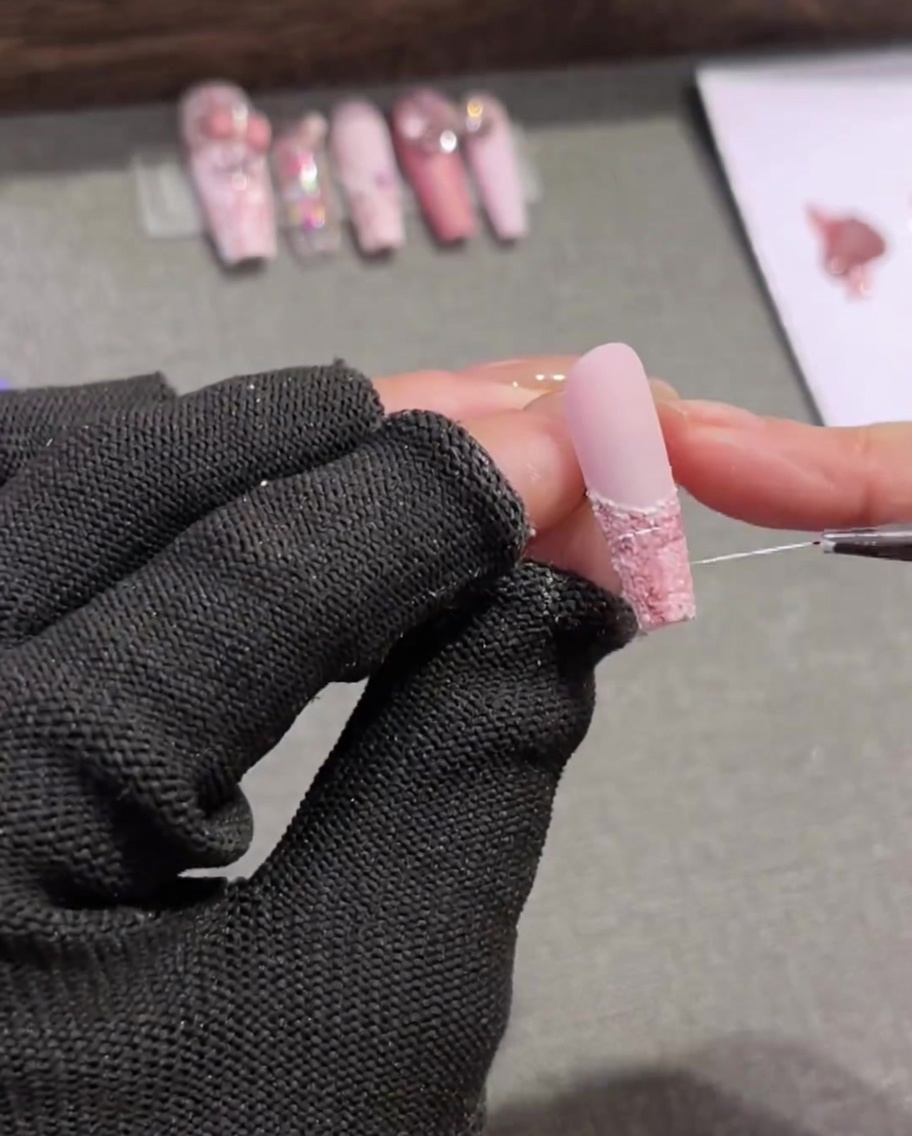 Un pennello liner molto lungo e sottile traccia linee bianche casuali su un design tweed rosa e marrone.