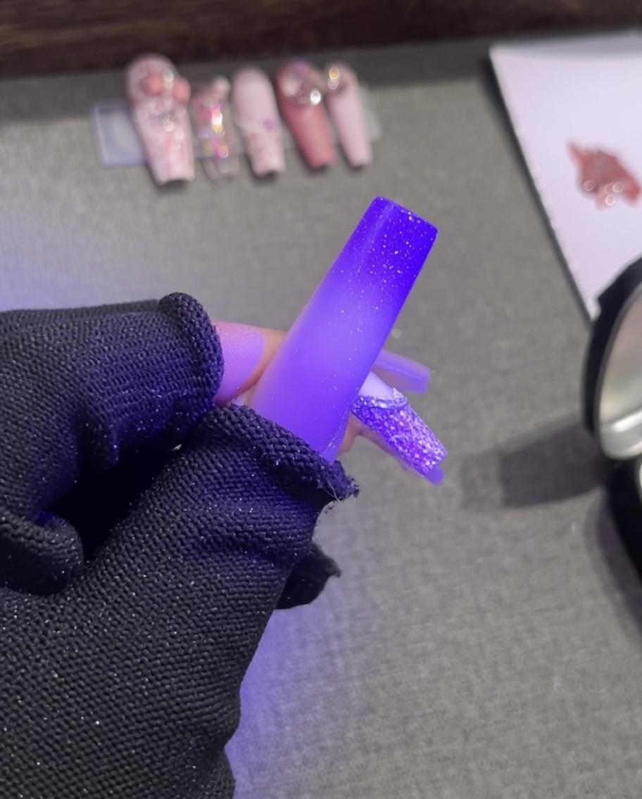 Pinzette posizionano una perla bianca su un bordo di gel plastilina fresco.