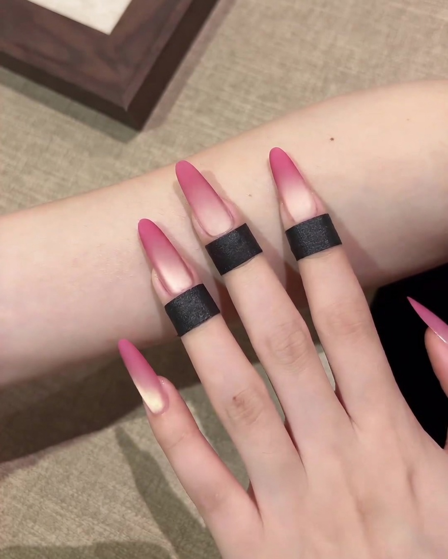 Un primo piano che mostra una spugnetta per trucco applicare il gel cat-eye rosa sulla punta di ununghia.