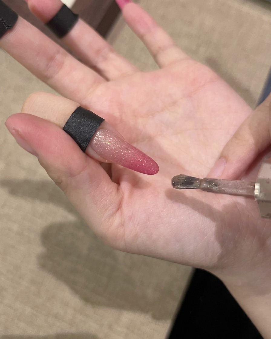 Una mano tiene un magnete parallelo a ununghia per attrarre le particelle magnetiche brillanti.