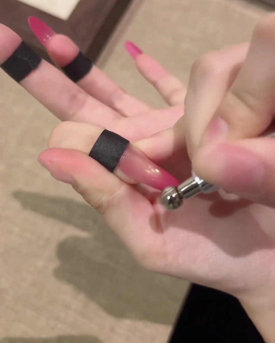 Una mano riposa allinterno di una lampada per unghie UV professionale per polimerizzare il design in gel cat-eye finito.