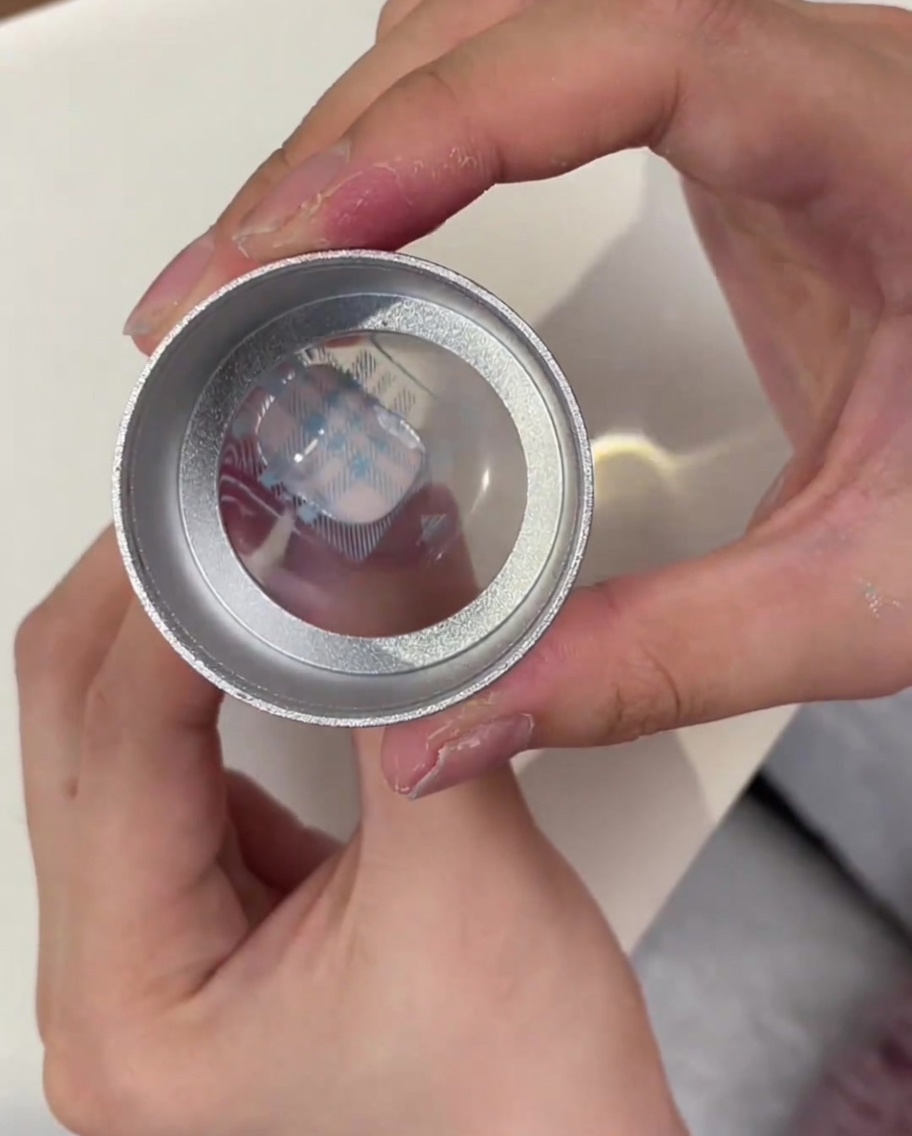 Una testa di stamper in gel trasparente che mostra il motivo plaid blu prelevato dal disco metallico.