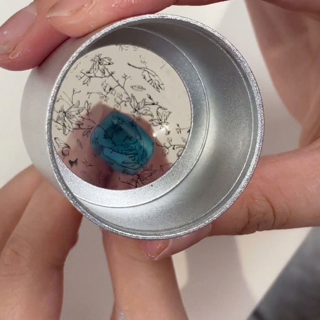 Uno stamper in gel trasparente tenuto sopra ununghia turchese, che mostra il motivo floreale nero posizionato per il trasferimento.