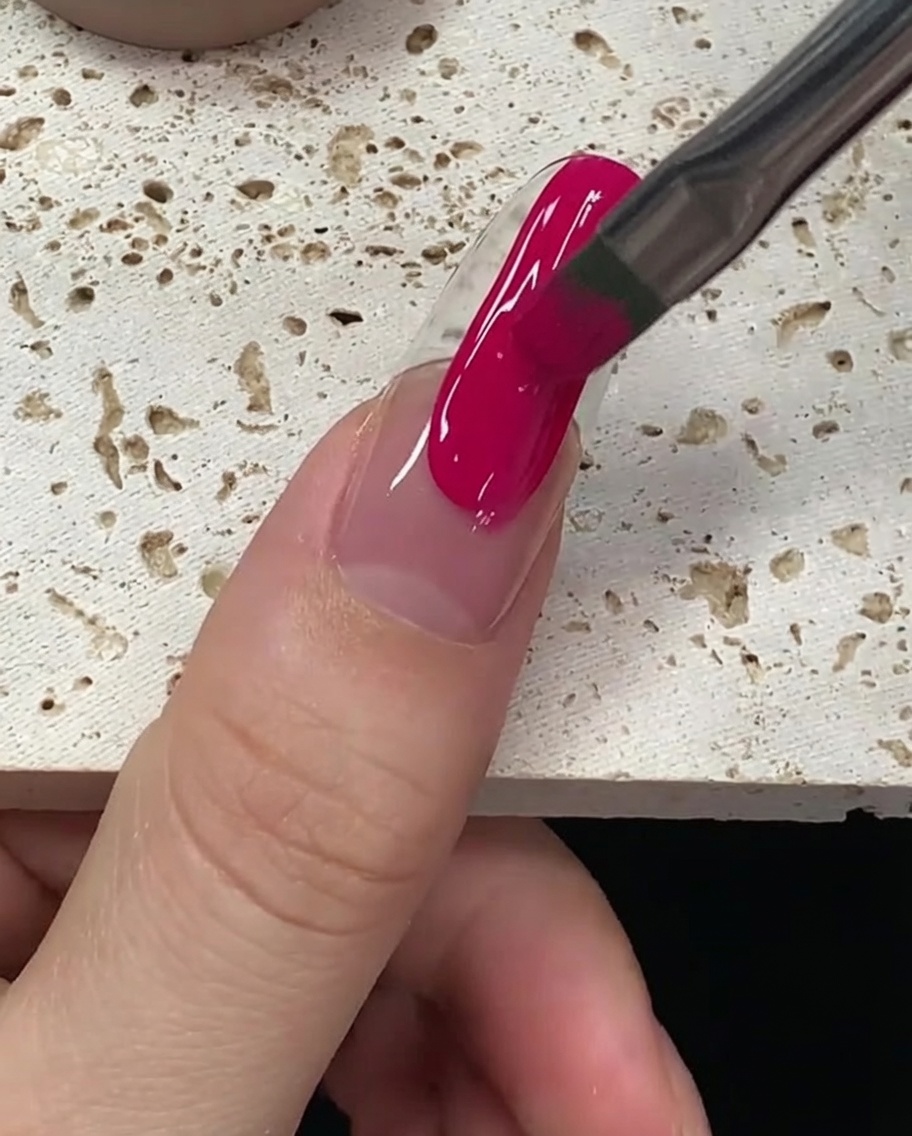 Il pennello che uniforma lo smalto gel magenta per assicurare una copertura totale e impeccabile.