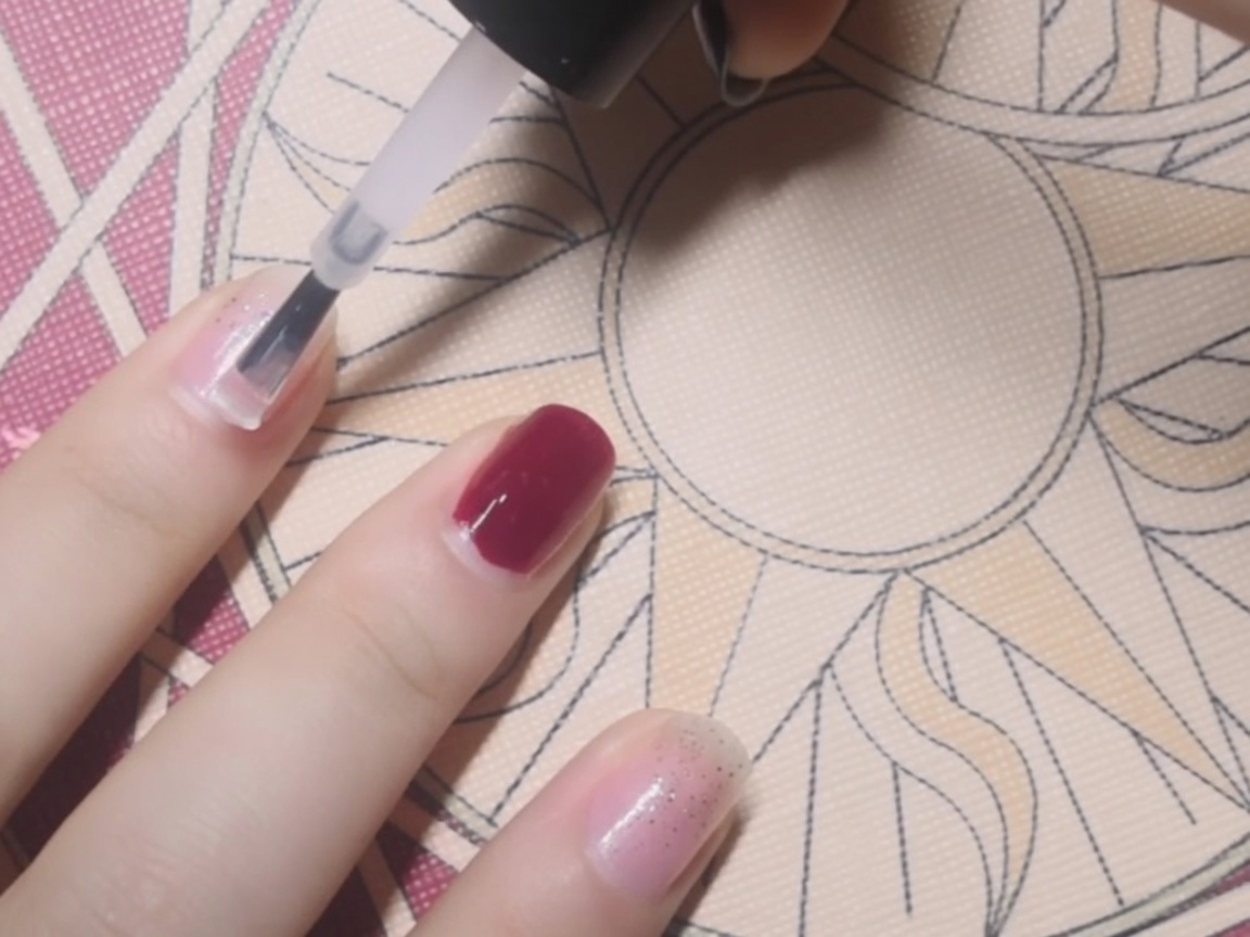 Primo piano dellapplicazione di una base coat trasparente su ununghia.